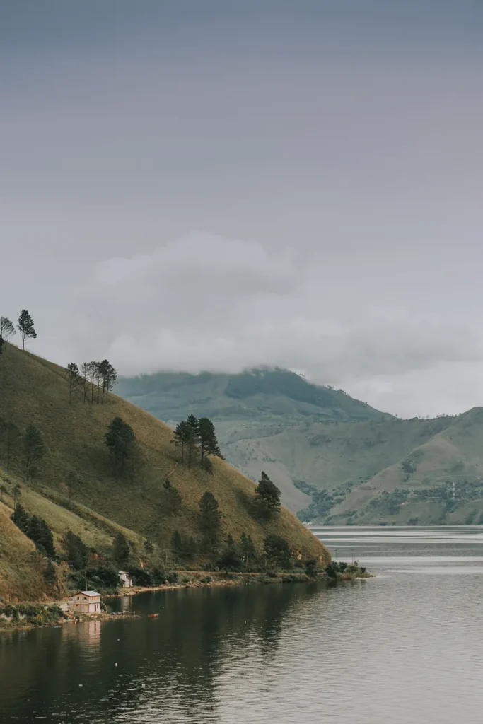 Majestic view of Lake Toba surrounded by rolling hills and foggy skies in North Sumatra, Indonesia.