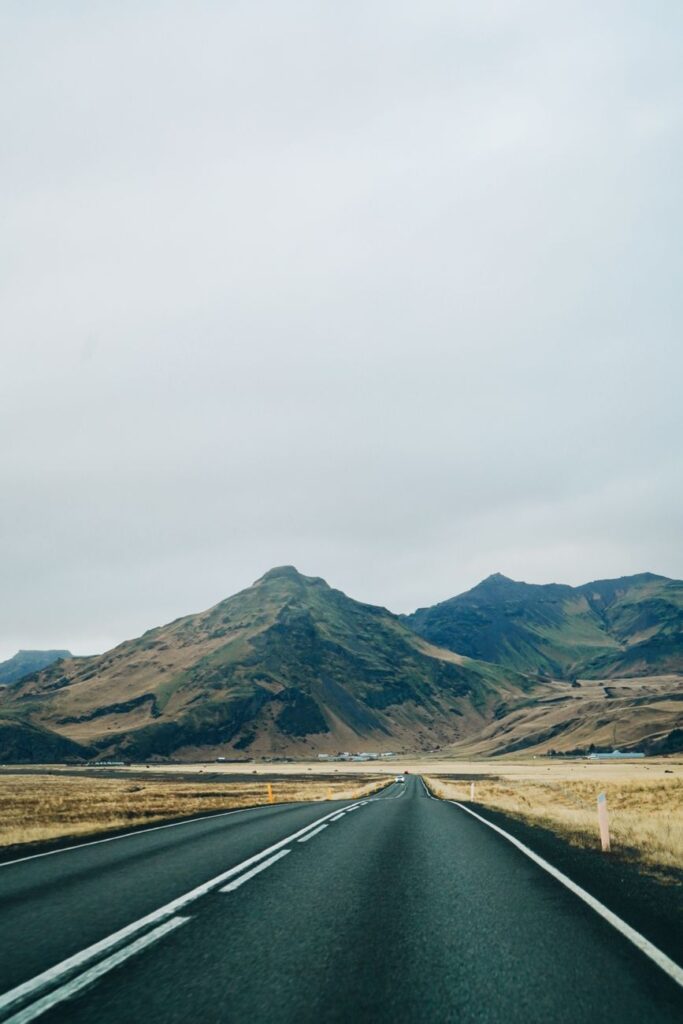 Open road through a scenic mountainous landscape under a cloudy sky, offering a tranquil journey.