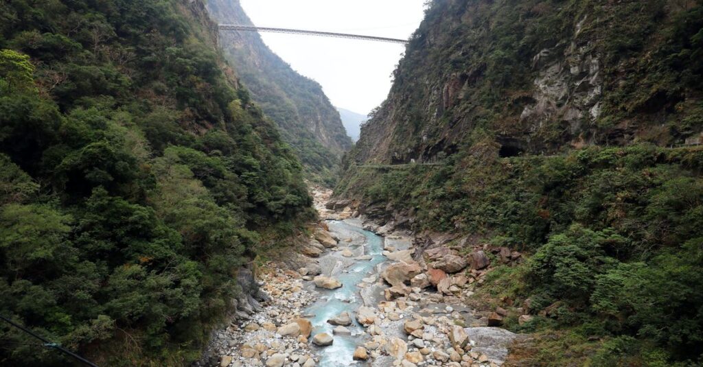 Zhuilu Old Trail à deux dans le parc de Taroko : le guide concret (sans se cramer) Panoramic view of a bridge over a river amidst lush green mountains in Taroko Gorge, Taiwan.