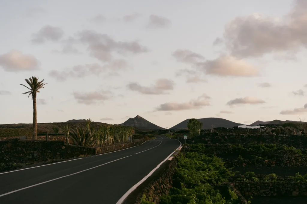 Peaceful evening view of a winding road in Lanzarote, with volcanic hills and sparse greenery.