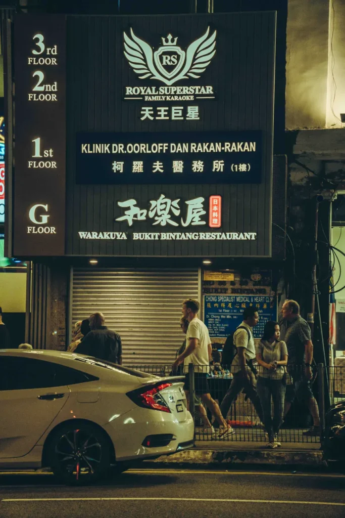 People walk past the vibrant streets of Bukit Bintang in Kuala Lumpur at night.