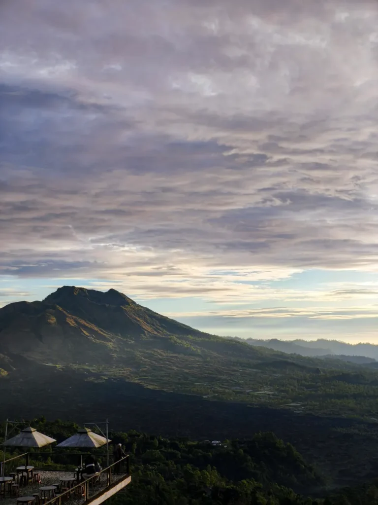 Scenic view of Mount Batur in Bali at sunrise with dramatic clouds.
