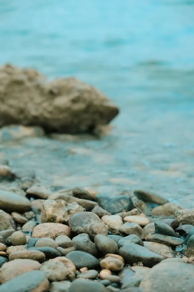 Serene pebbled beach with clear turquoise waters and smooth stones under the summer sun.