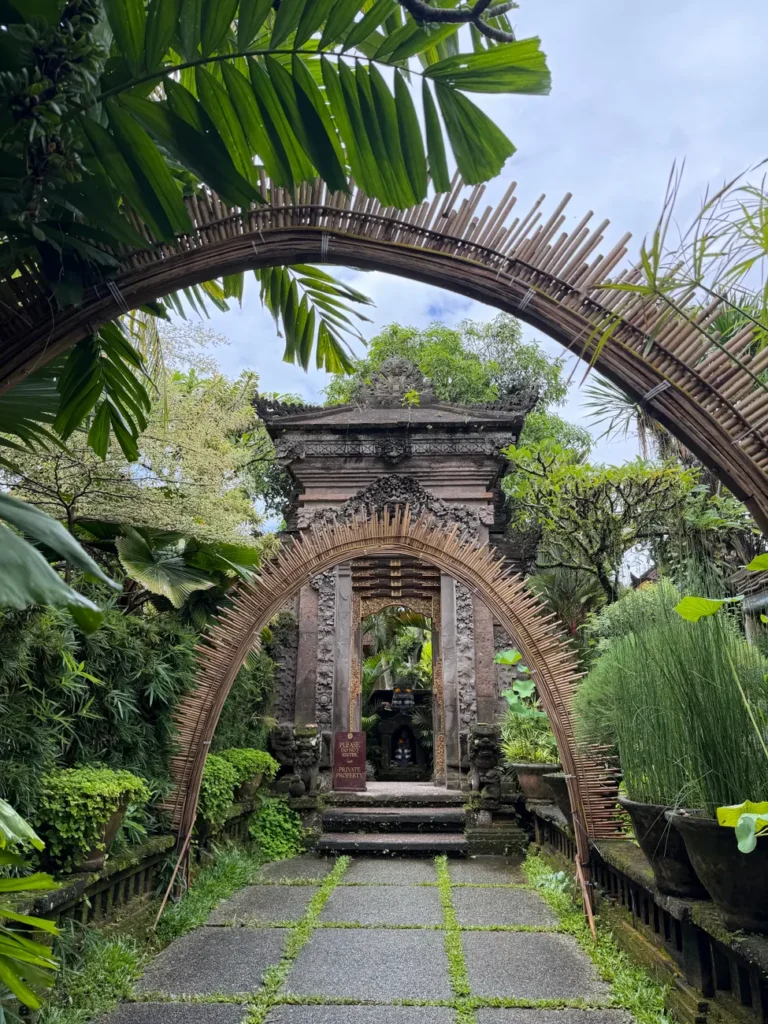 Serene temple entrance in Bali adorned with bamboo structures and lush greenery.