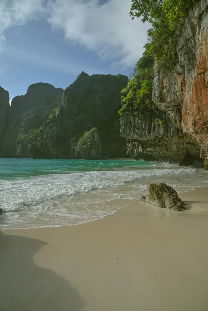 Serene tropical beach with turquoise water, soft sand, and dramatic limestone cliffs.