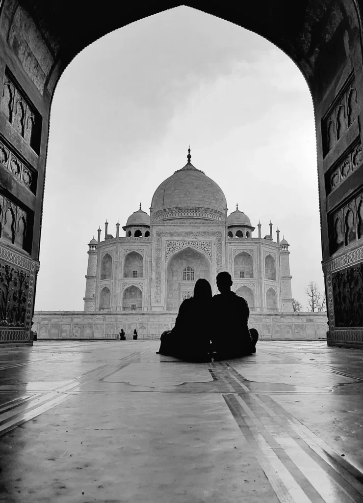 Silhouette of a couple sitting before the iconic Taj Mahal in grayscale.