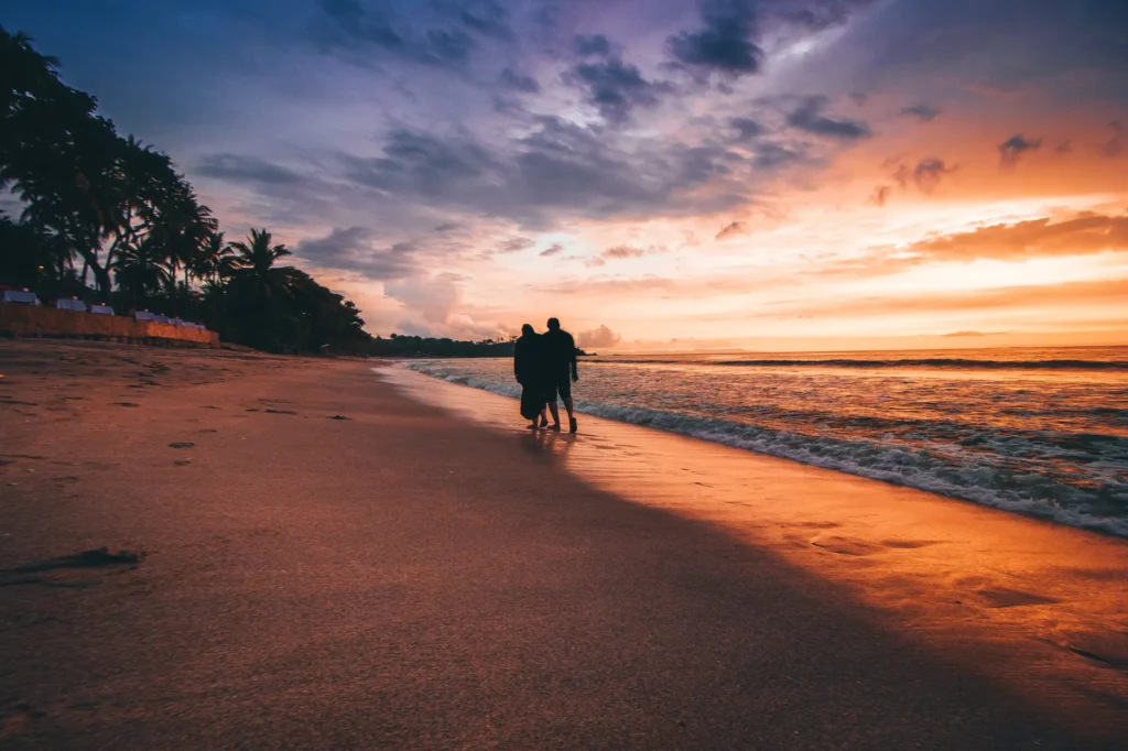 Silhouette of a couple walking along a beach in Indonesia during a stunning sunset.