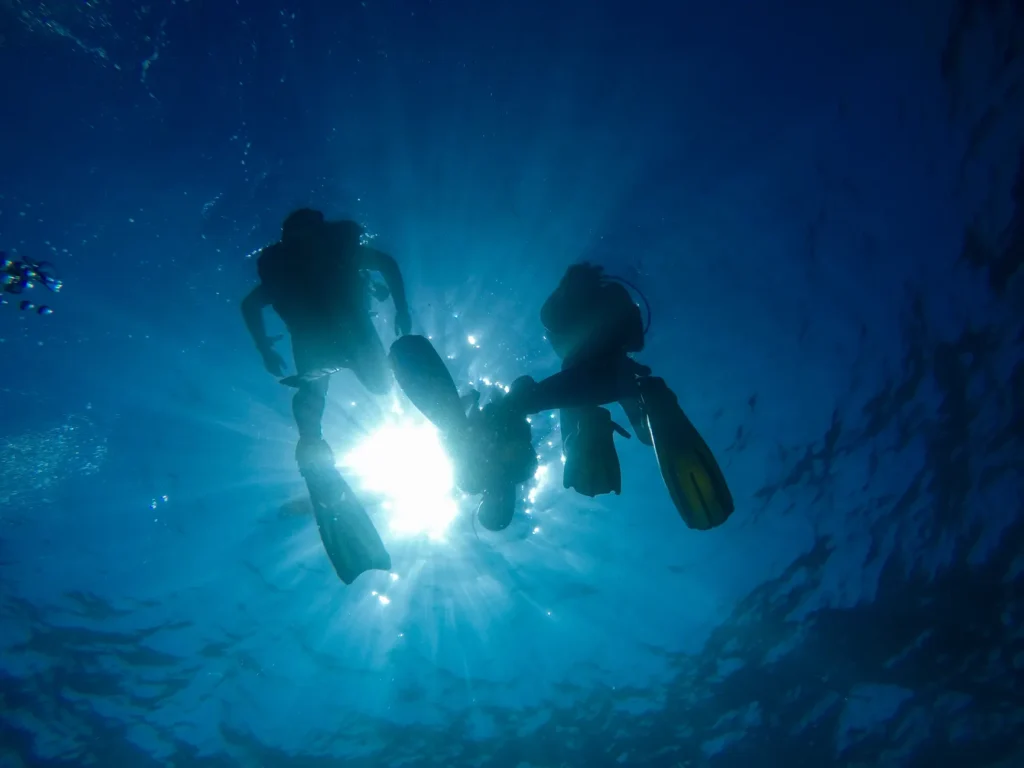 Silhouette of scuba divers with sun rays underwater in Koh Tao, Thailand.