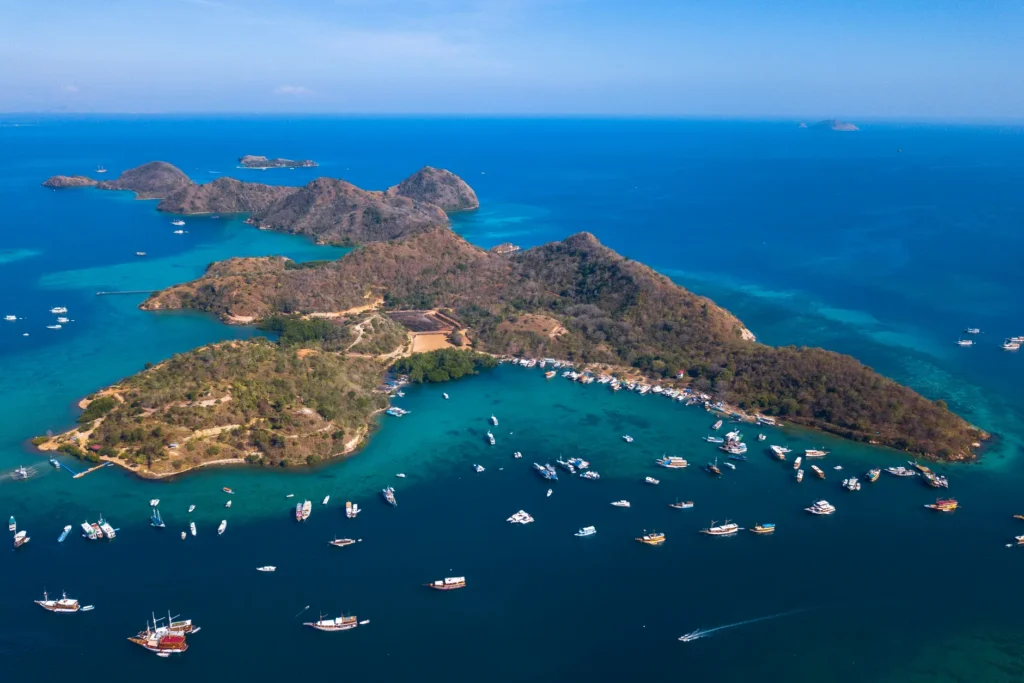 Stunning aerial photograph of Labuan Bajo islands in East Nusa Tenggara, showing vibrant blue waters and numerous boats.