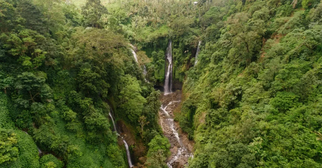 Sekumpul à deux : la cascade géante de Bali, sans vous faire piéger par les “guides” Stunning aerial view of cascading waterfalls surrounded by lush green rainforest.