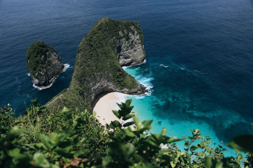 Stunning aerial view of Nusa Penida's picturesque beach in Bali surrounded by clear turquoise waters and lush green cliffs.