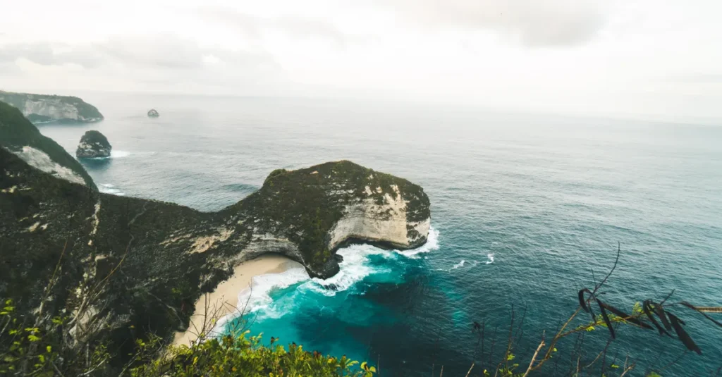Nusa Penida à deux : le guide concret pour 4 jours “bleu, cliff & moments à nous” Stunning aerial view over Kelingking Beach on Nusa Penida, showcasing cliffs and turquoise ocean waters.