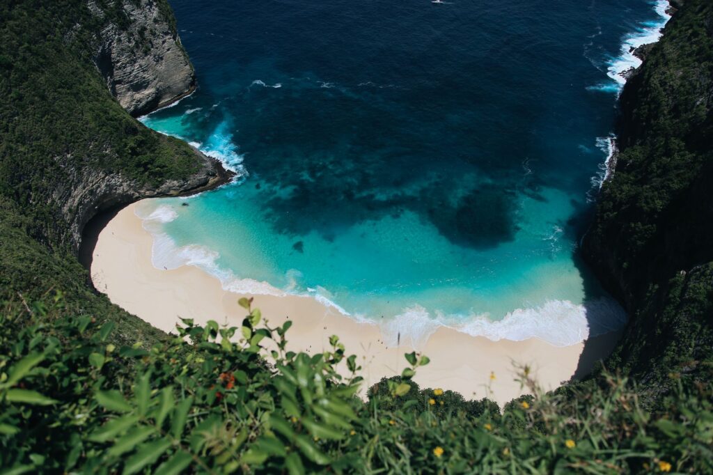 Stunning high-angle view of the turquoise waters and sandy beach at Kelingking Beach, Nusa Penida, Bali.