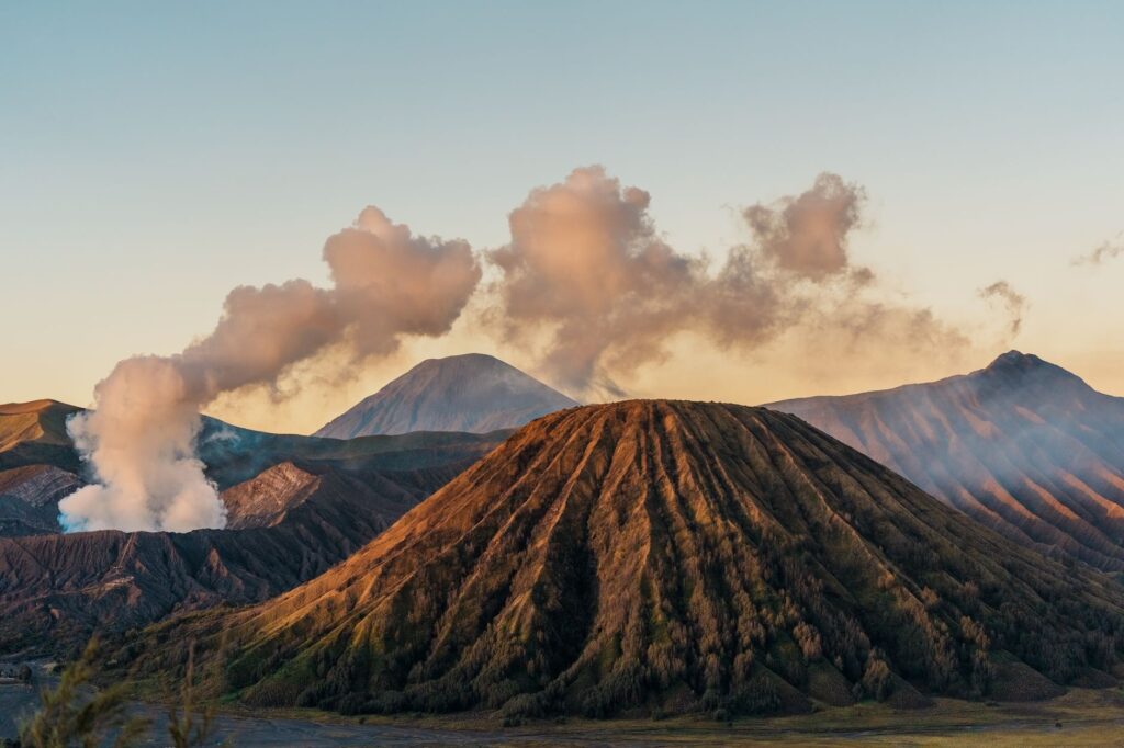 Sunrise over Mount Bromo in East Java, showcasing volcanic landscape and steam clouds.