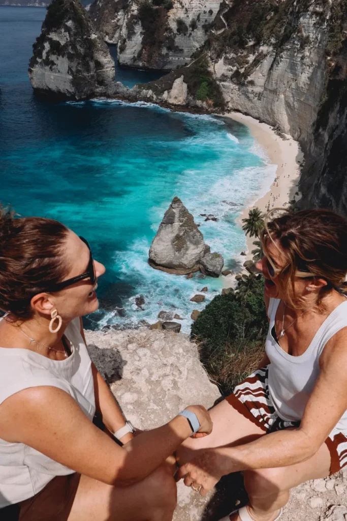 Two women enjoy the dramatic coastal view at Nusa Penida, Bali. Perfect travel moment.