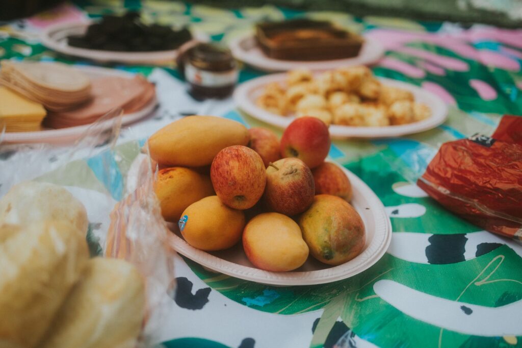 Vibrant picnic scene with fruits and snacks on a colorful blanket, perfect for a summer day outdoors.