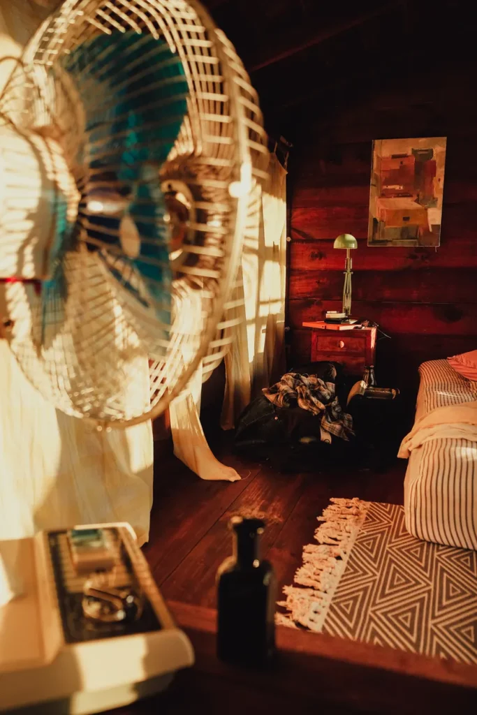 Warm and inviting bedroom scene with an electric fan and wooden interiors.
