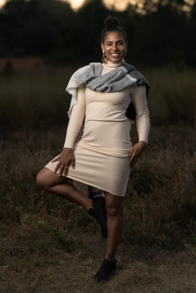 Woman dressed in a neutral dress and scarf posing outdoors, exuding confidence and style.