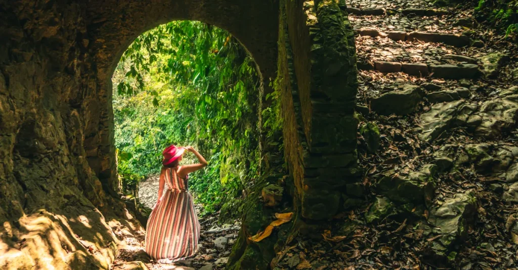 Goa Garba à deux : ruines dans la jungle de Pejeng (Bali), sans se faire aspirer par la foule Woman in pink hat exploring mystical ruins in lush Cuetzalan, Mexico jungle.