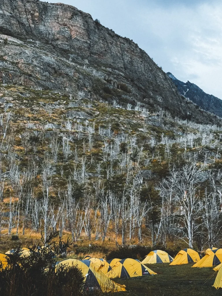 Yellow tents nestled at the base of rugged Patagonian mountains in Chile.